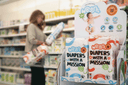 A customer shopping in the supermarket and putting 2 packs in her basket.